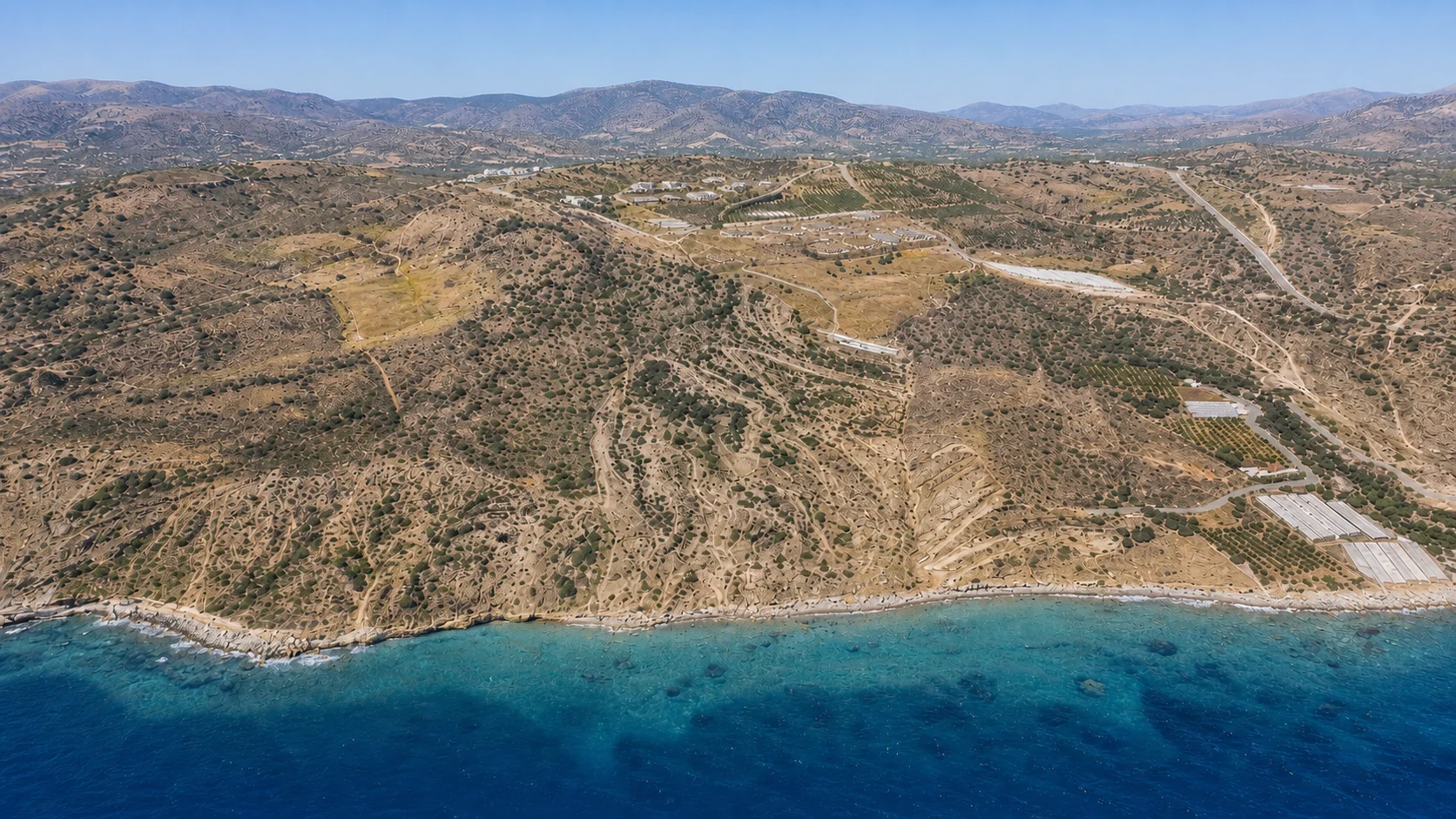 The coastline seen obliquely from the sea, olive terraces rising to the mountains behind